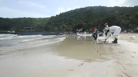 OIL SPILL DISASTER WORKERS CLEAN TROPICAL BEACH Stock Footage 27645467