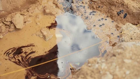 Oil spill polluting puddle water in desert sand Stock Footage 341294541