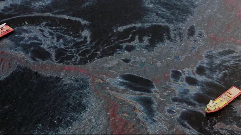 Oil spill pollution floating on ocean surface with boats Stock Footage 334980943