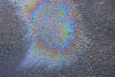 Oil Spills Create Colorful Patterns on Asphalt Surface in Urban Area After Rain Stock Photos