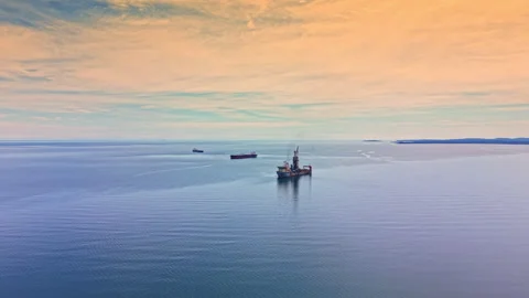 Oil tanker moves through open sea under blue sky with some clouds at dusk in a Stock Footage 340133419