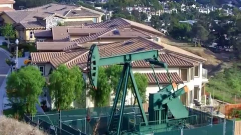 Oil well pumping rig extracts petroleum in a suburban neighborhood Stock Footage 98578905
