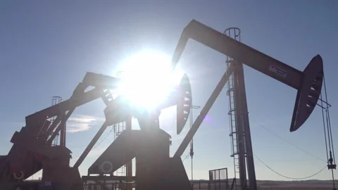 Oil well pumpjacks group of three back lit Stock Footage 265495784