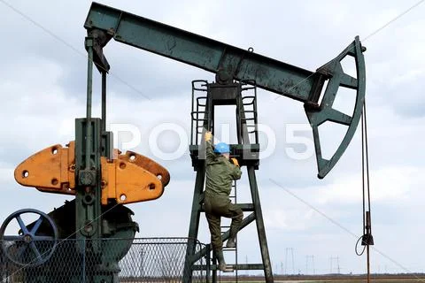 Oil worker climbs to the pumpjack.JPG Stock Photos