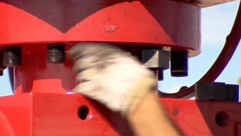 Oil worker tightens nuts on fracking equipment in petroleum field C Stock Footage 125685063