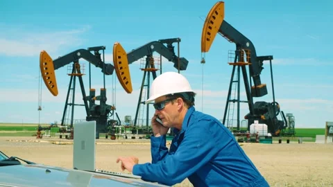 Oilfield worker using a laptop computer on hood of car on location at oil field Stock Footage 163162426