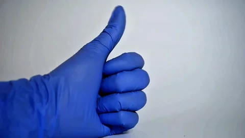 Ok sign is showed by left hand in a blue medical glove on a white background. Stock Footage 307327405