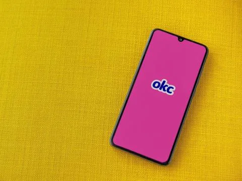 OkCupid app launch screen with logo on the display of a black mobile smartpho Stock Photos