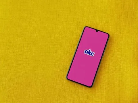 OkCupid app launch screen with logo on the display of a black mobile smartpho Stock Photos