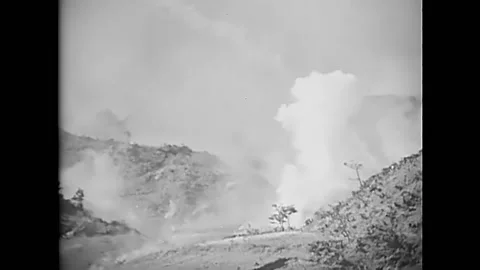 OKINAWA - 1945 - Shells explode, and a 37mm gun crew carries a gun up a hill in 動画素材 287744798