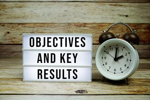 OKR - Objective Key Results text on LED lightbox with alarm clock on wooden.. 库存照片