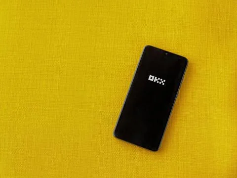 OKX app launch screen on smartphone on yellow fabric background Stock Photos