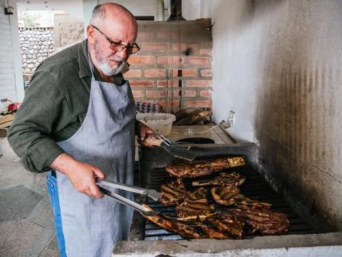 Ol man cooking Tomahawk rib beef steak on hot black grill Stock Photos
