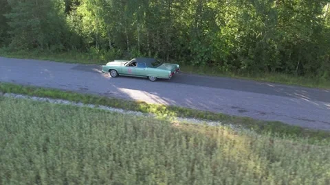 Old 70's historic and unique car driving on green landscapes and roads Stock Footage 230079095