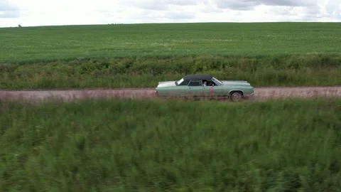 Old 70's historic and unique car driving on green landscapes and roads Stock Footage 230079118