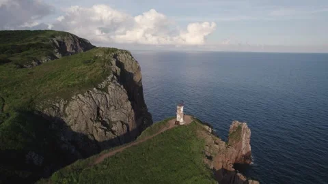 An old abandoned lighthouse on top of a red-orange cliff, footage taken from Stock Footage 246024028
