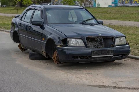 Old abandoned rusty car without license plates and wheels on the side of the  Stock Photos