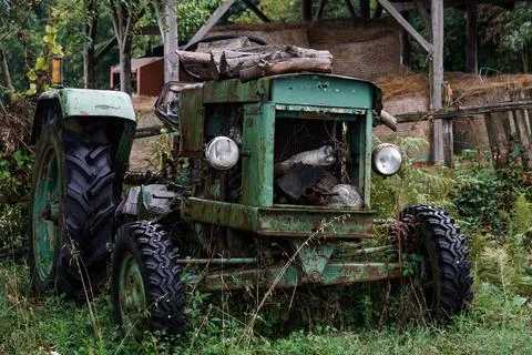 An old, abandoned, rusty tractor sits in a lush green field. Stock-Fotos