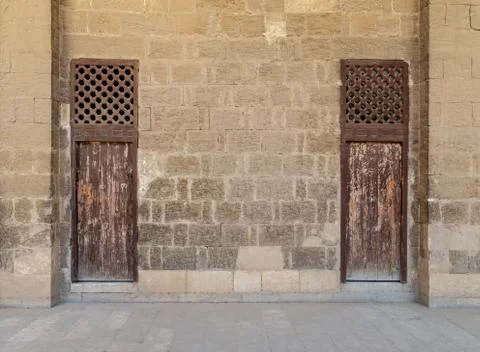Old abandoned stone bricks wall with two weathered wooden doors Foto stock