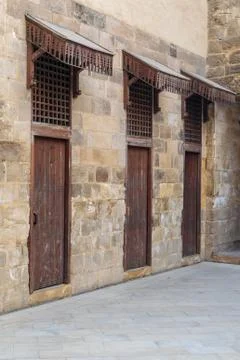 Old abandoned stone bricks wall with three weathered wooden doors Stock Photos