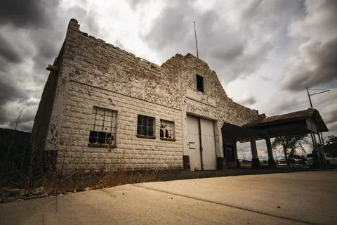 Old abandoned stone building under dark stormy clouds Stock Photos