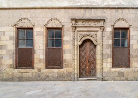 Old abandoned stone decorated bricks wall with arched wooden door and three Stock Photos