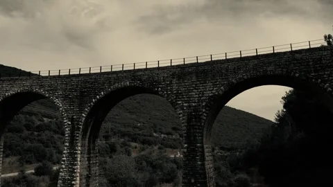Old abandoned stone train bridge over the river Vidéo 346487060
