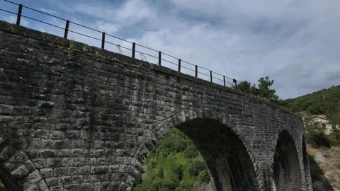 Old abandoned stone train bridge over the river Vidéo 346487074
