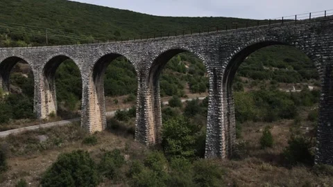 Old abandoned stone train bridge over the river Vidéo 346487174