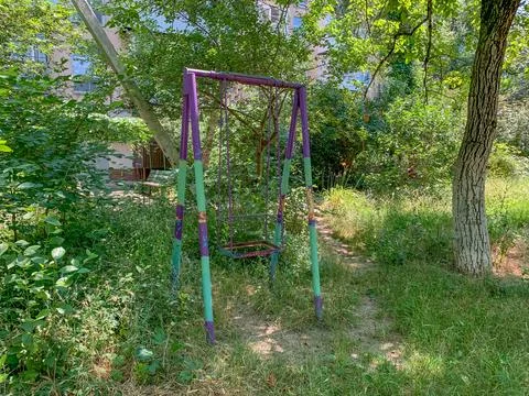 Old abandoned swing in the courtyard of a multi-story building Stock Photos