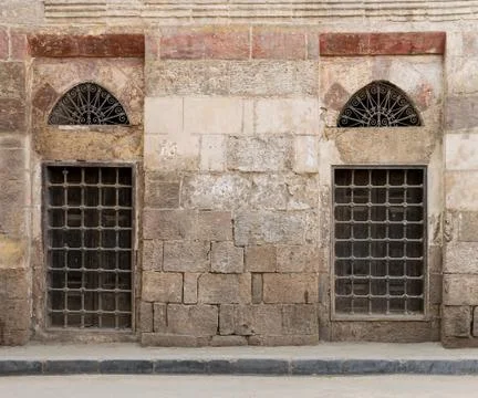Old abandoned wall with two closed decorated wooden windows Stock Photos