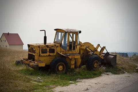 Old abandoned yellow front loader parked on a rural roadside Stock Photos