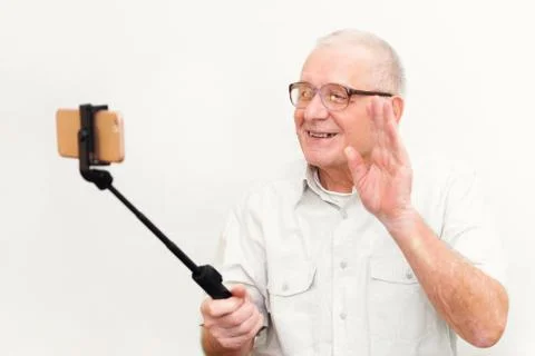 Old active man taking selfie with mobile phone isolated on grey background Stock Photos
