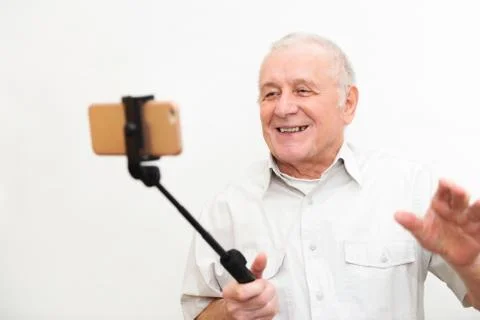 Old active man taking selfie with mobile phone isolated on grey background Stock Photos