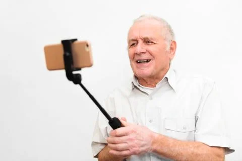 Old active man taking selfie with mobile phone isolated on grey background Stock Photos