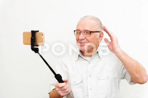 Old active man taking selfie with mobile phone isolated on grey background Stock Photos