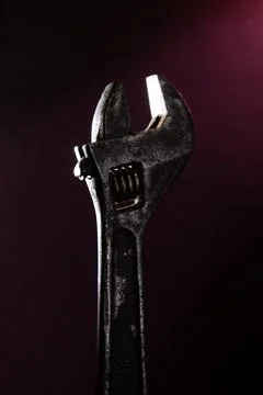Old adjustable wrench in backlight with a red light on the background. Stock Photos