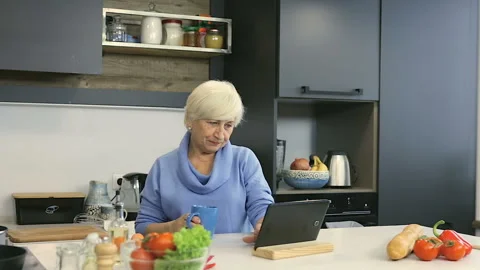 Old aged couple at the kitchen. Looking recipe (or watching news). Stock Footage 102327232