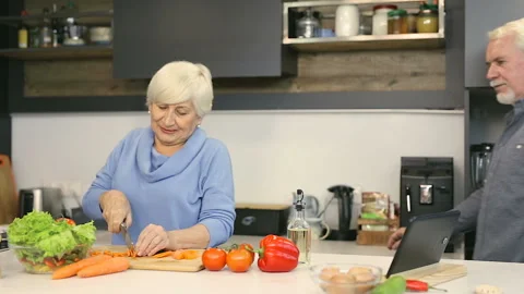 Old aged couple. Man joking and taking peace of carrot . Stock Footage 102449545