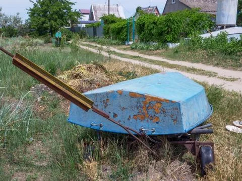 Old-aged rust-colored boat bottom at near village houses. Stock Photos