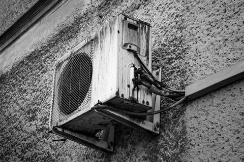 Old air conditioning unit mounted on a textured wall in black and white Stock Photos