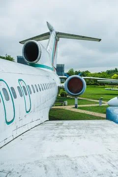 An old airplane is parked on grass with a cloudy sky above. Other aircraft ca Stock Photos
