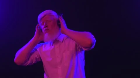 An old albino grandpa dancing while wearing earphones, isolated on a unique b Stock Footage 137516270