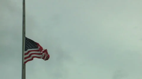 Old American flag flying at half mast against a cloudy sky Stock Footage 36987451