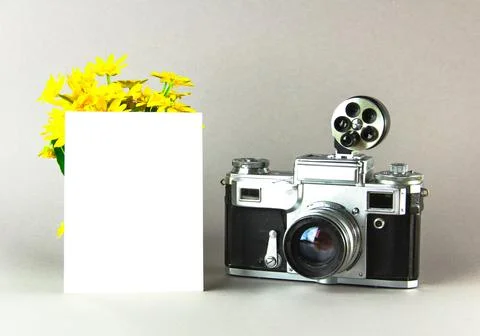 Old analog camera top view with a photo frame and a bouquet of flowers. Stock Photos