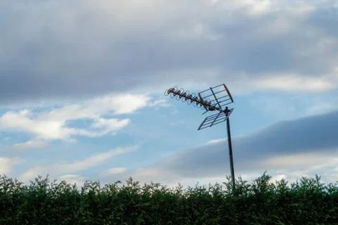 Old analogue reflective array antenna mounted to a mast behind a green hedge Stock Photos