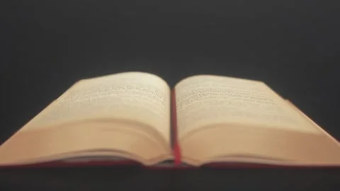 Old ancient open book on a dark background. The focus is on the pages of an open Stock Footage 285082458