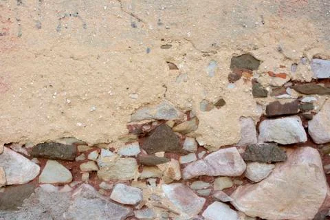 Old and damaged rustic rock wall with grainy finish peeling off. Rustic Stock Photos