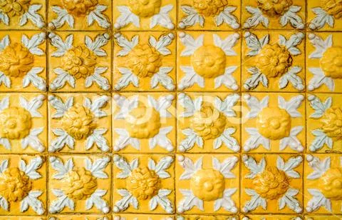Old and dirty bright yellow relief tiles with floral pattern. Vintage glazed Stock Photos