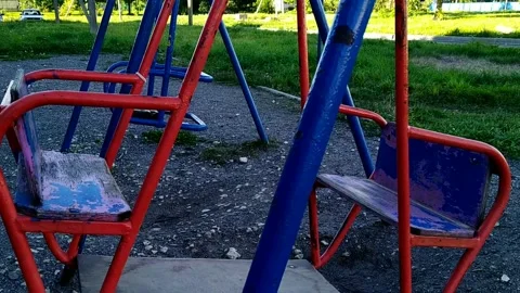 Old and empty swings move from side to side on the playground during the daytime 動画素材 209856685